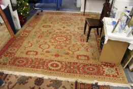 A large Persian style rug, beige ground with broad floral decoration.