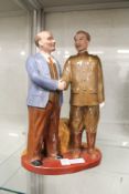 A Russian pottery group of two figures standing shaking hands.