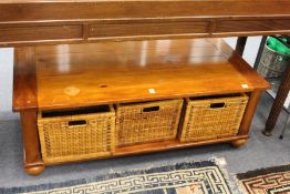 A modern coffee table fitted with three wicker baskets.
