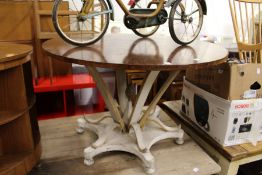 A circular dining table with polished hardwood top and decorative painted base.