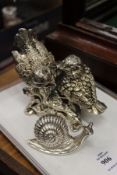 A silvered model of a pair of birds and a similar snail.