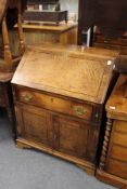 A George III oak bureau with a drop flap, over a single drawer and pair of cupboard doors.