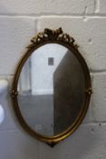 A gilt framed oval mirror.
