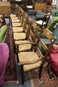 A set of eight modern oak ladder back dining chairs with rush seats, two with arms.