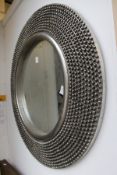 A circular wall mirror with decorative silver coloured frame.