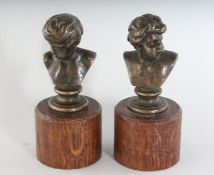 A SMALL PAIR OF GRAND TOUR BRONZE BUSTS on wooden bases. 3.5ins high.