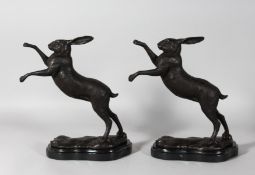 A GOOD PAIR OF BRONZE BOXING HARES on a shaped marble base. 11ins high.