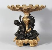 A GOOD BRONZE AND GILT BRONZE COMPORT with three cupids and dolphin support. 13ins high.