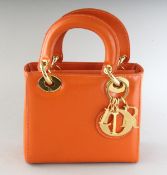 AN ORANGE LEATHER HANDBAG. 6.5ins wide.