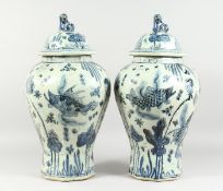 A PAIR OF 20TH CENTURY CHINESE BLUE AND WHITE BALUSTER SHAPE TEMPLE JARS AND COVERS, painted with