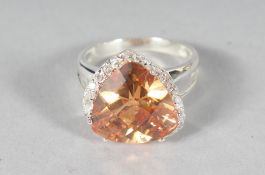 A SILVER ORANGE CZ HEART SHAPED RING.