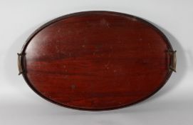 AN OVAL MAHOGANY TRAY WITH BRASS CARRYING HANDLES. 22ins wide.