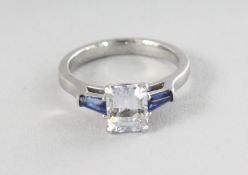 A PLATINUM OCTAGON WHITE SAPPHIRE RING, 1.65cts, and two blue sapphires, 0.32cts, on the shoulders.
