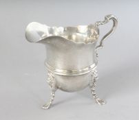 A HELMET SHAPED SILVER MILK JUG on three claw feet. Chester 1898.
