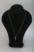 A 9CT GOLD DIAMOND SET CROSS on a chain.