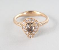 AN 18CT YELLOW GOLD PEAR SHAPED CHAMPAGNE DIAMOND RING, 0.57cts, surrounded by eighteen rose