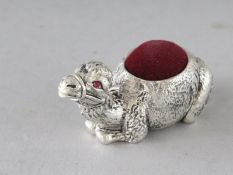 A PLATED CAMEL PIN CUSHION. 2.25ins