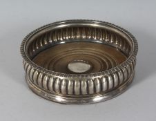 A GEORGE III SILVER WINE COASTER with turned wood base. 5.5ins diameter. London 1817.