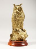 A CAT BRASS MODEL OF AN OWL ON A TREE STUMP, mounted on a circular wooden base. 12ins high.