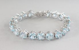 A SILVER AND ROUND CUT BLUE TOPAZ LINE BRACELET.