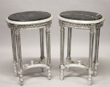 A GOOD PAIR OF SILVERED OVAL TABLES with marble tops. 28ins high.