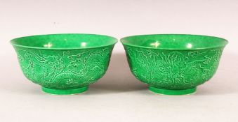A PAIR OF CHINESE GREEN GROUND MOULDED DRAGON BOWLS, 16cm diameter.