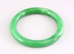 A CHINESE GREEN JADE BANGLE, 8.5cm diameter.