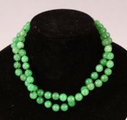 A STRING OF JADE BEADS, 66cm long.