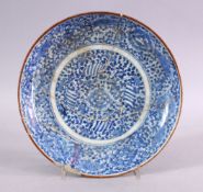 AN EARLY SAFAVID BLUE & WHITE PORCELAIN PLATE, decorated with scrolling floral design, (AF) 22cm.