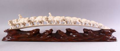 AN UNUSUAL EARLY 20TH CENTURY CARVED IVORY TUSK BRIDGE, on wooden stand, carved as a group of eleven