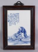 A GOOD CHINESE BLUE & WHITE PORCELAIN FRAMED TILE OF LUOHAN AND CHILDREN, in a landscape setting,