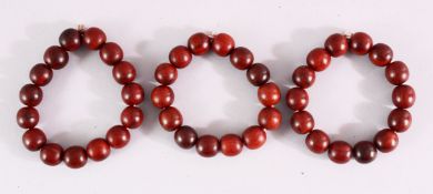 THREE RED SANDLEWOOD BEAD BRACELETS and various loose beads.