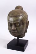 A CAMBODIAN CARVED STONE BUST OF A MAN, mounted on a plinth base, overall height 28cm.