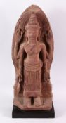 A 12TH CENTURY STYLE CAMBODIAN KHMER STYLE RED SANDSTONE CARVING OF A FOUR ARMED DEITY. 52cms high.