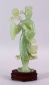 A CHINESE CARVED JADE FIGURE OF GUANYIN, stood holding a bouquet above her head, on a wooden