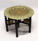 A GOOD LARGE ISLAMIC BRASS TRAY TABLE AND FOLDING STAND, with embossed decoration, 76cm diameter.