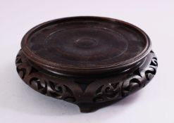 A 19TH CENTURY CHINESE CARVED HARDWOOD STAND, with carved frieze and stood upon four feet, housing a