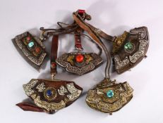 FIVE 19TH CENTURY LEATHER BETEL NUT POUCHES with ornate embossed and applied decoration.
