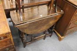 An oak oval drop leaf gate leg table with a drawer to one end.