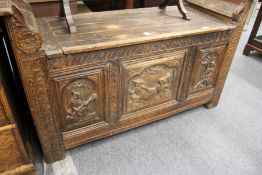 A continental carved oak settle with lifting lid and triple carved panelled front.