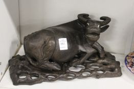 A Chinese 19th century carved hardwood model of a water buffalo on a pierced and carved stand.