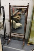 A 19th century mahogany cheval mirror with turned supports on four curving legs with brass castors.
