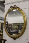 A gilt framed oval wall mirror.