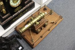 A good brass model of a canon on a wooden carriage with balustraded oak stand and accessories.