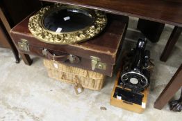 A gilt mirror, a leather suitcase, a wicker basket and a sewing machine.