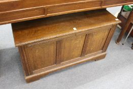An oak blanket box with panelled front and ends.