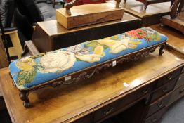 A Victorian beadwork upholstered fender footstool with carved decoration.