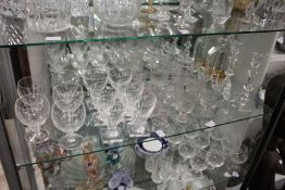 A quantity of good cut glass drinking glasses, a pair of candlesticks and a decanter.