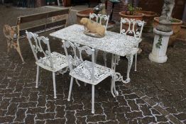 A white painted cast aluminium rectangular patio table and four chairs.