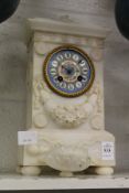 A carved alabaster mantle clock with Sevres style porcelain dial (some losses).